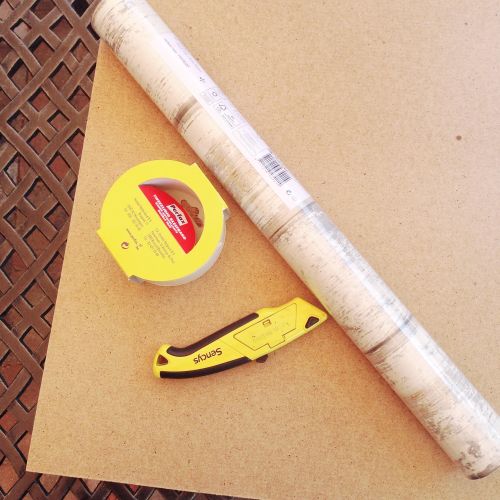 What you need to make your DIY Photography Backdrop: Sheet of lightweight plywood, wallpaper, double-sided tape and a Stanley Knife