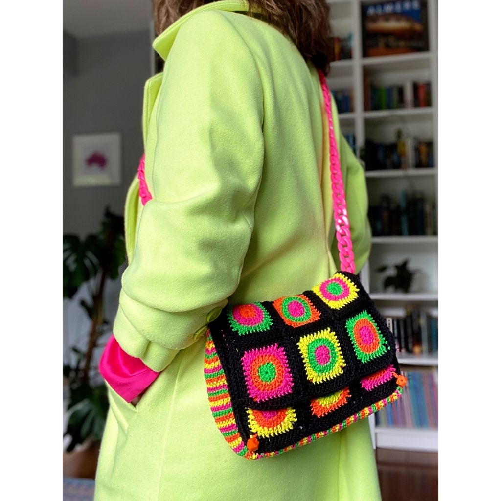 close up of woman wearing cross-body crochet bag in neon colours